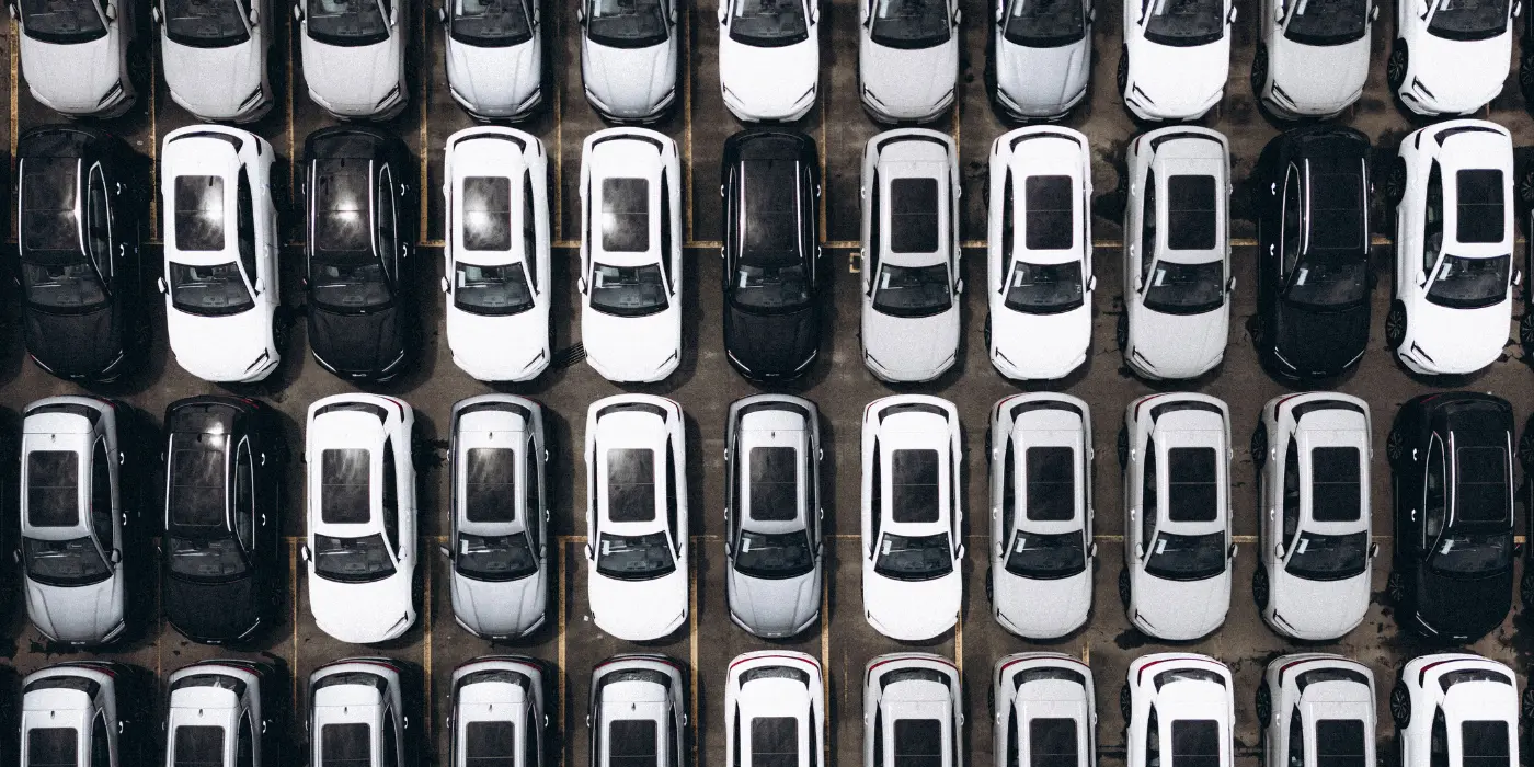 Vorteile im Fuhrparkmanagement Eine Luftaufnahme eines riesigen Parkplatzes, der dicht an dicht mit hunderten Fahrzeugen gefüllt ist. Nur wer Fuhrparkmanagement beherrscht, kann die Flotte optimieren.